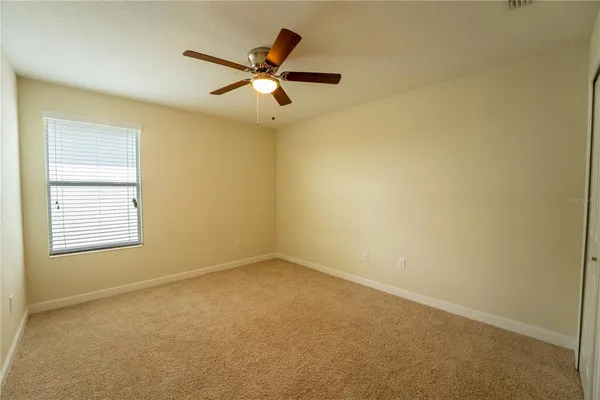 an empty room with a ceiling fan and a window