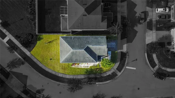 a view of a white house with a swimming pool and lawn chairs under an umbrella