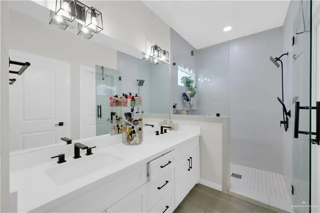 a bathroom with a double vanity sink a large mirror a bathtub and shower