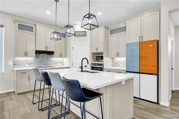 a kitchen with stainless steel appliances kitchen island granite countertop a sink a stove a refrigerator and island with wooden floor