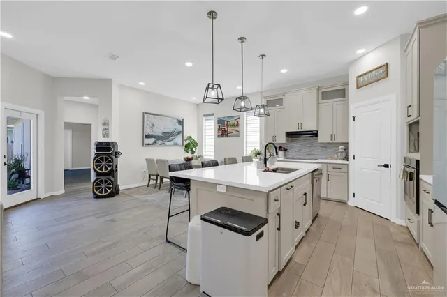 a kitchen with a sink stainless steel appliances and wooden floor