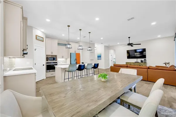 a living room with stainless steel appliances furniture a rug and a kitchen view