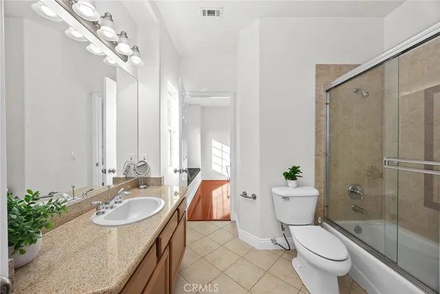 a bathroom with a granite countertop sink a toilet a mirror and shower