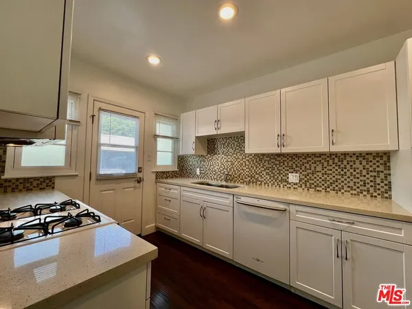 a kitchen with stainless steel appliances white cabinets and a stove top oven