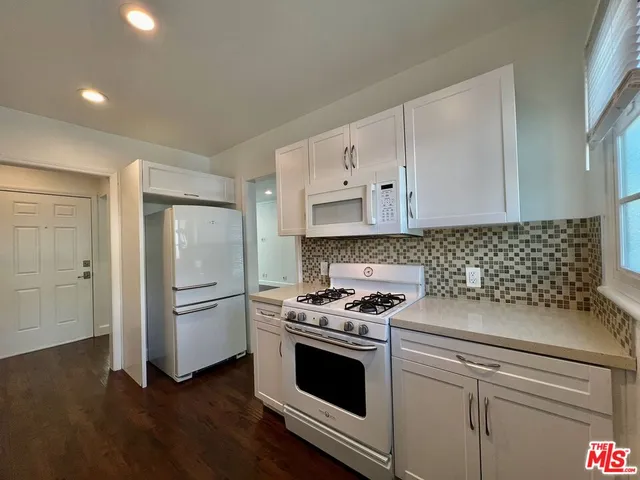 a kitchen with granite countertop white cabinets and appliances