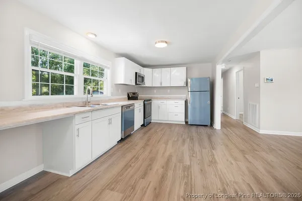 a view of a kitchen with a sink and dishwasher with wooden floor