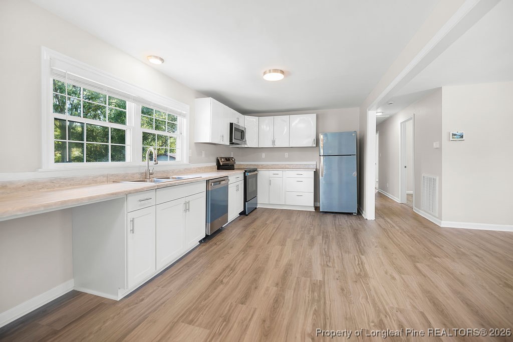 4066 Hummingbird Place Fayetteville, NC 28312 - Photo 12 of 30 a view of a kitchen with a sink and dishwasher with wooden floor