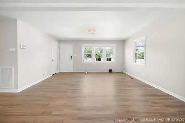 an empty room with wooden floor and windows