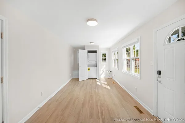 a view of an empty room with a window and wooden floor