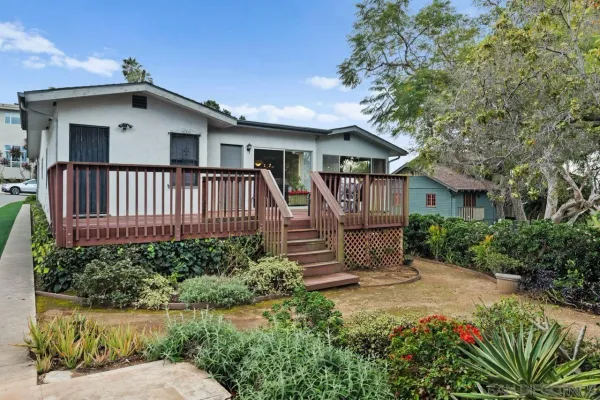 a view of a house with wooden fence next to a yard