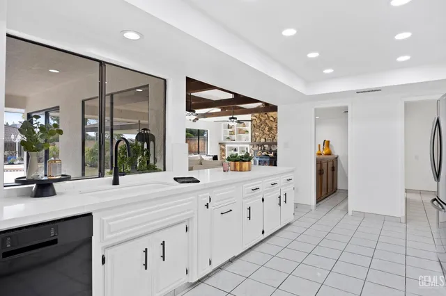a large white kitchen with a large window and stainless steel appliances