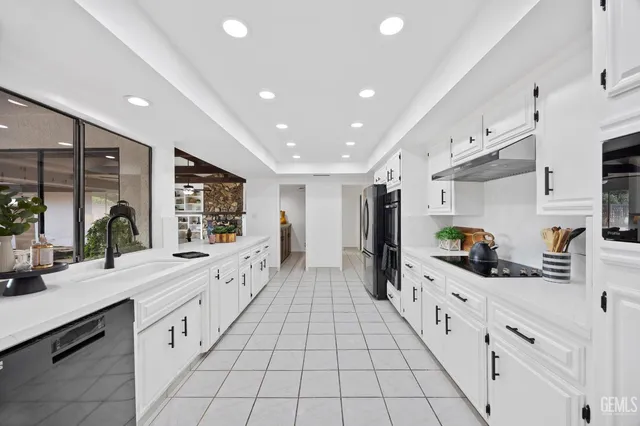 a large white kitchen with stainless steel appliances lots of counter space and wooden floor