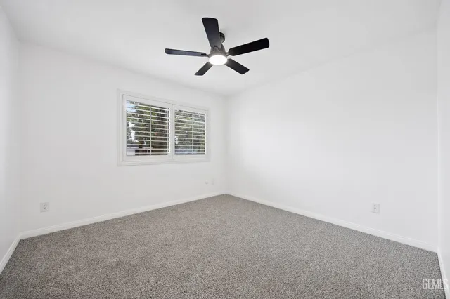 an empty room with ceiling fan and window