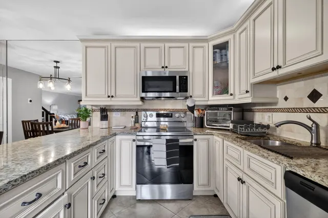 a kitchen with granite countertop white cabinets and stainless steel appliances