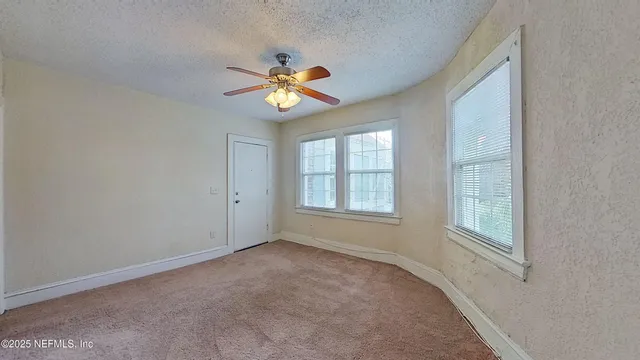 an empty room with a window and a fan