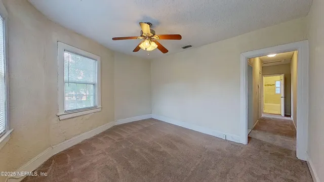 an empty room with windows and fan