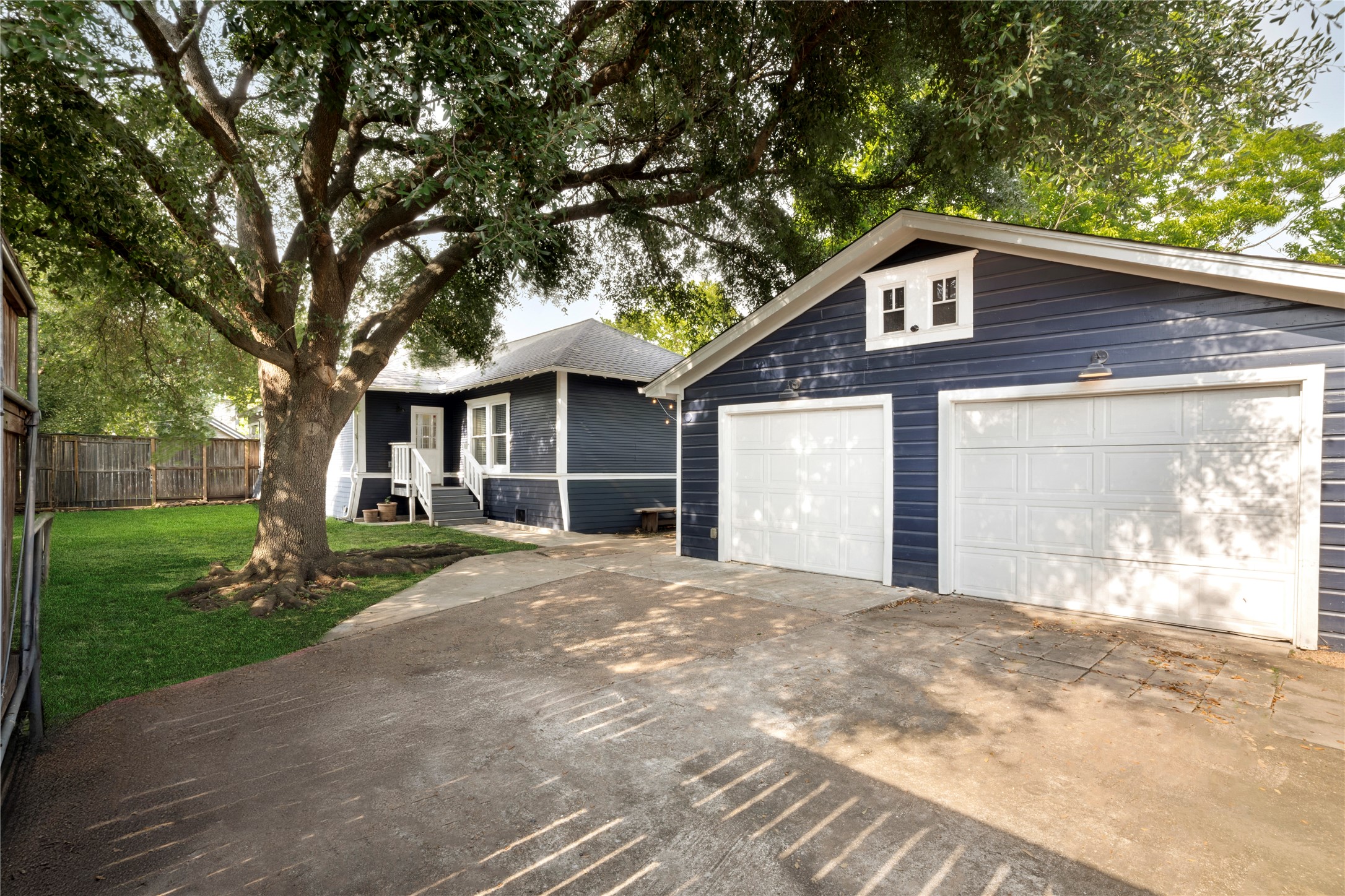 602 Aurora Street Houston, TX 77008 - Photo 26 of 36 Driveway and rear approach framed by mature trees and fencing, creating a sense of privacy as you enter. Smart security features including Yale keyless entry locks and integrated cameras extend to the exterior of the home. A functional approach that blends everyday access with added convenience and security.
