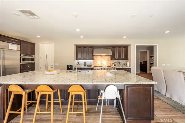 a kitchen with granite countertop lots of wooden cabinets a sink and stainless steel appliances
