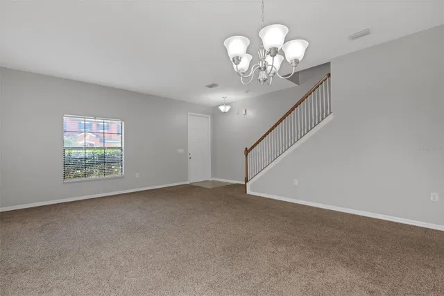 a view of an empty room with a chandelier fan