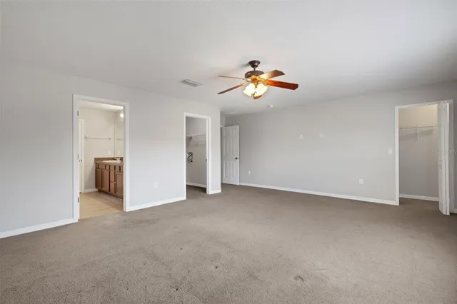 an empty room with a kitchen and chandelier fan