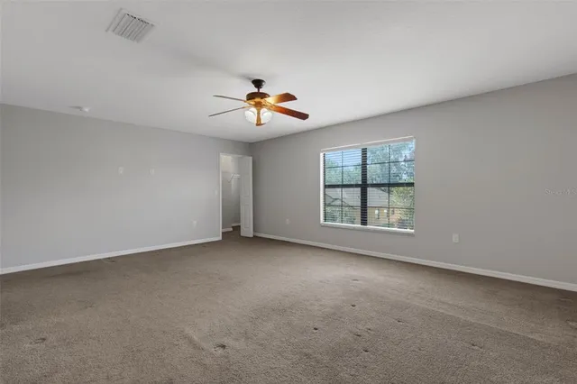 an empty room with windows and chandelier fan
