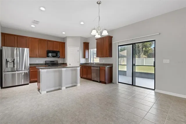 a kitchen with stainless steel appliances a refrigerator a stove a sink a center island a stove and a cabinets