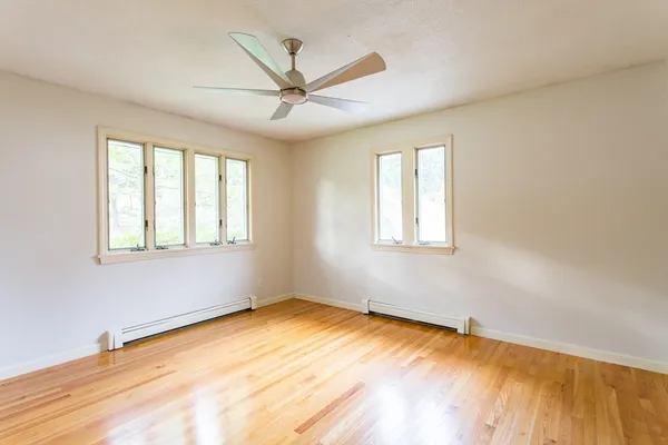 a view of a big room with wooden floor and windows