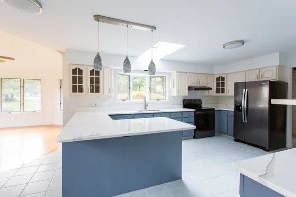 a large kitchen with kitchen island a large counter top stainless steel appliances and cabinets