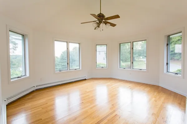 a view of an empty room with a window and wooden floor
