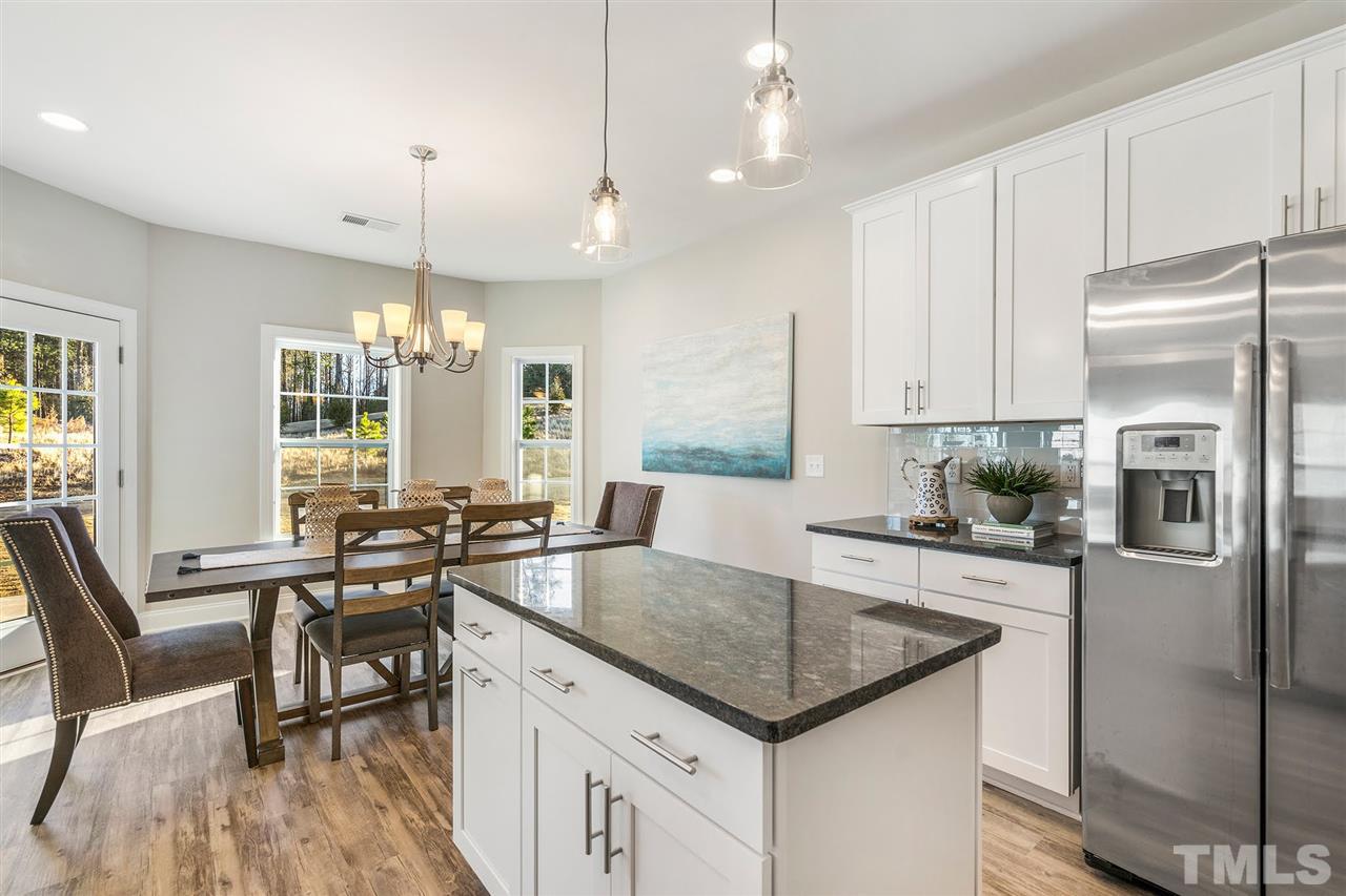 112 Edmer Lane Garner, NC 27529 - Photo 4 of 24 a kitchen with granite countertop a refrigerator a stove a sink a dining table and chairs