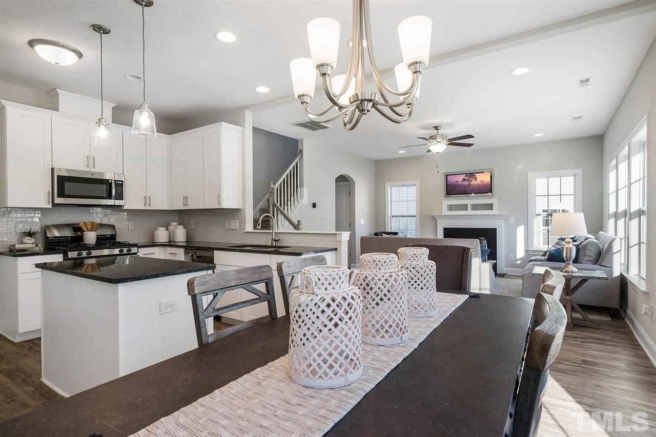 112 Edmer Lane Garner, NC 27529 - Photo 6 of 24 a kitchen with stainless steel appliances granite countertop a stove top oven a refrigerator a sink a dining table and chairs with wooden floor