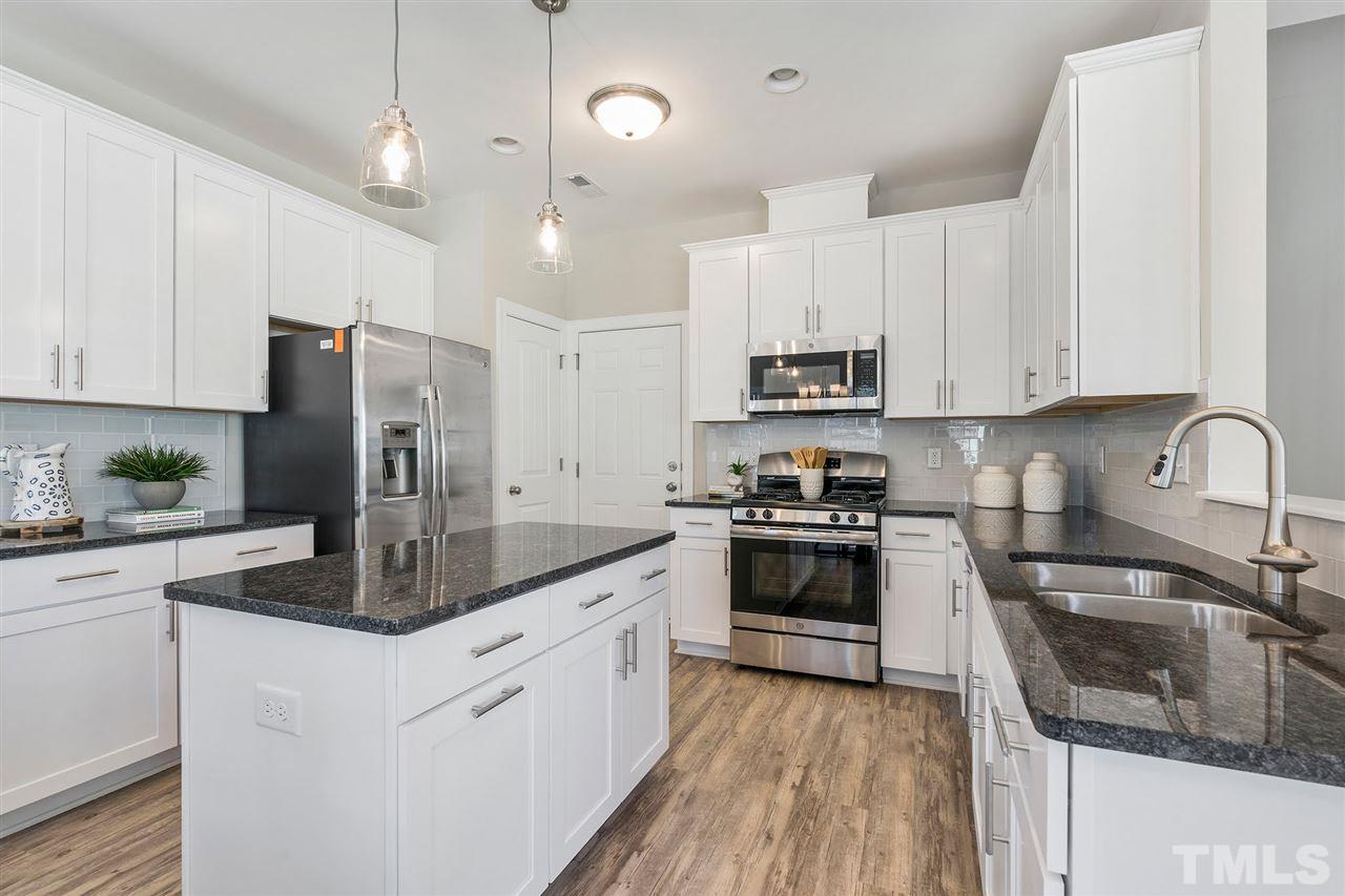 112 Edmer Lane Garner, NC 27529 - Photo 8 of 24 a kitchen with stainless steel appliances granite countertop a stove a sink dishwasher a refrigerator and white cabinets with wooden floor