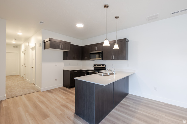 693 West 4500th South, Unit O101 Mapleton, UT 84664 - Photo 12 of 16 Kitchen with dark wood finish cabinetry, a peninsula, hanging light fixtures, stainless steel appliances, and light wood-type flooring