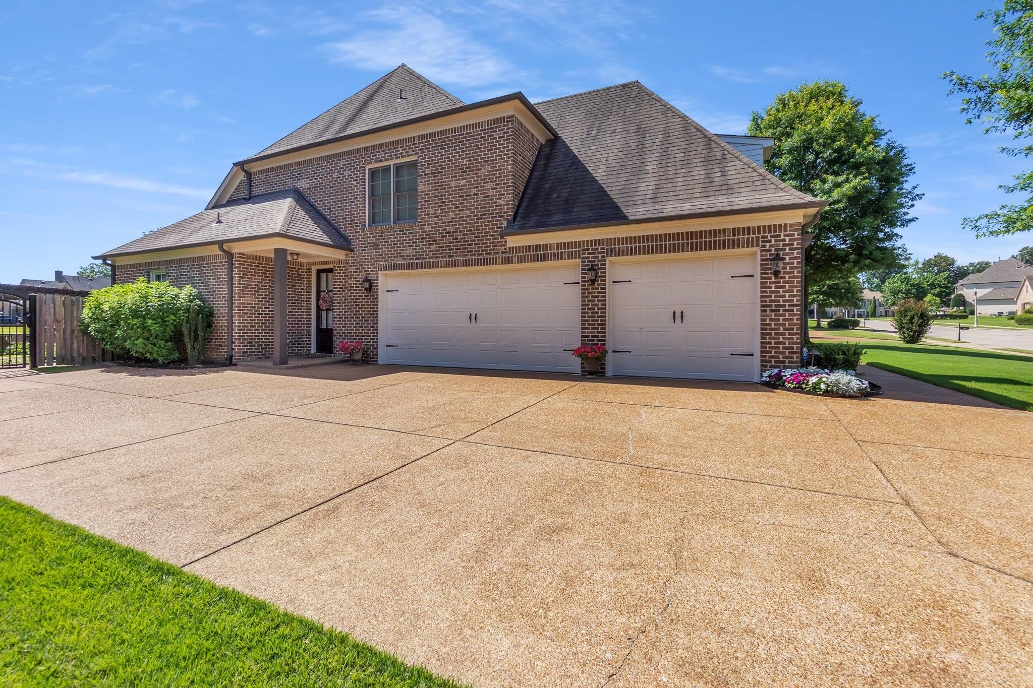 3246 North Hartwell Ridge Drive Collierville, TN 38017 - Photo 3 of 40 Brick exterior with a covered entry, two-car garage, and an exposed aggregate driveway
