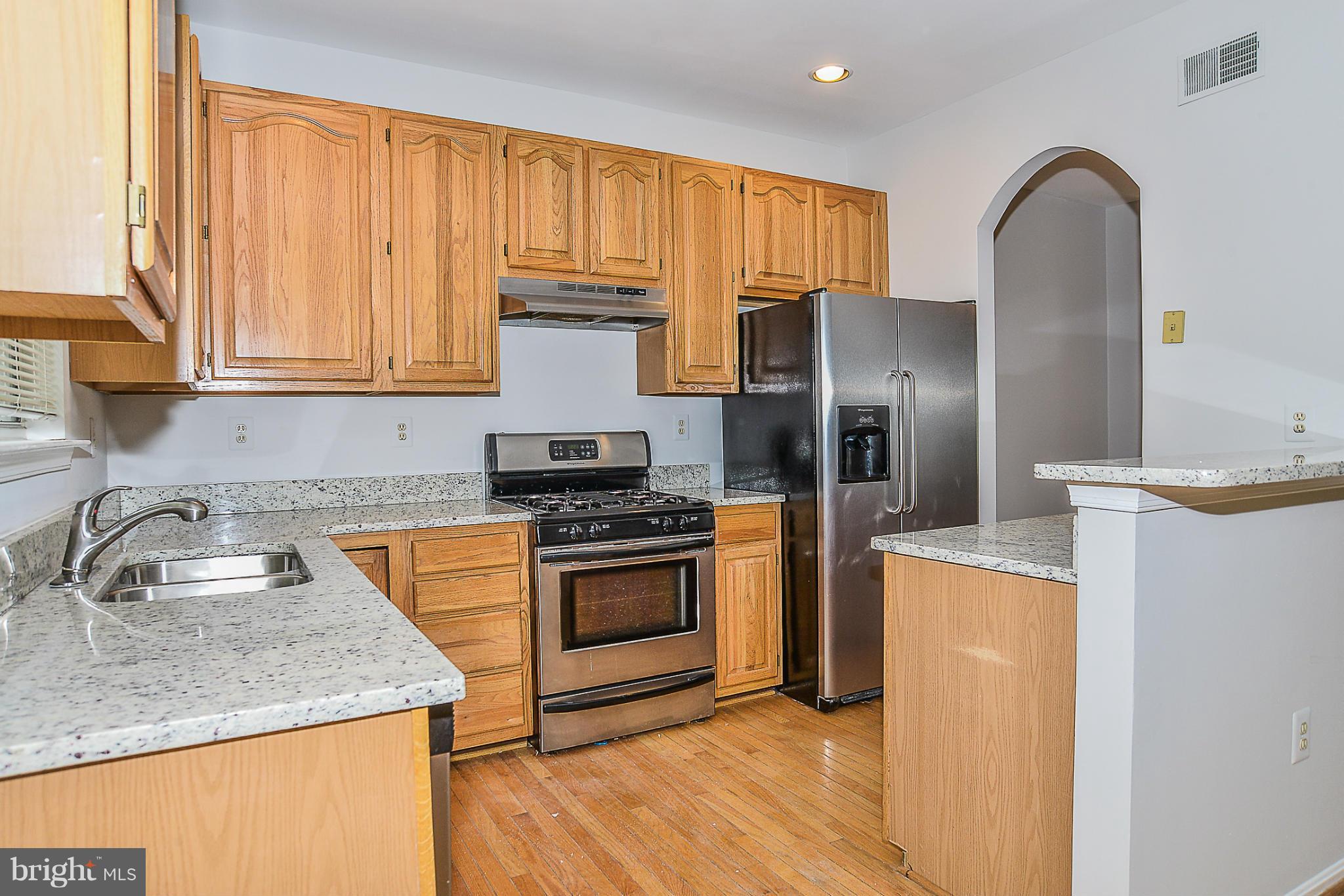 a kitchen with kitchen island granite countertop wooden cabinets stainless steel appliances and a window