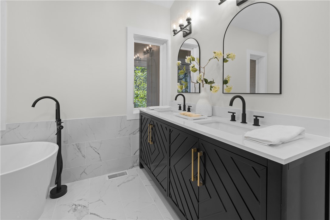 251 Riggs Drive Clemson, SC 29631 - Photo 24 of 37 Marble tiling complements a dark double vanity and a freestanding tub in this modern bathroom.