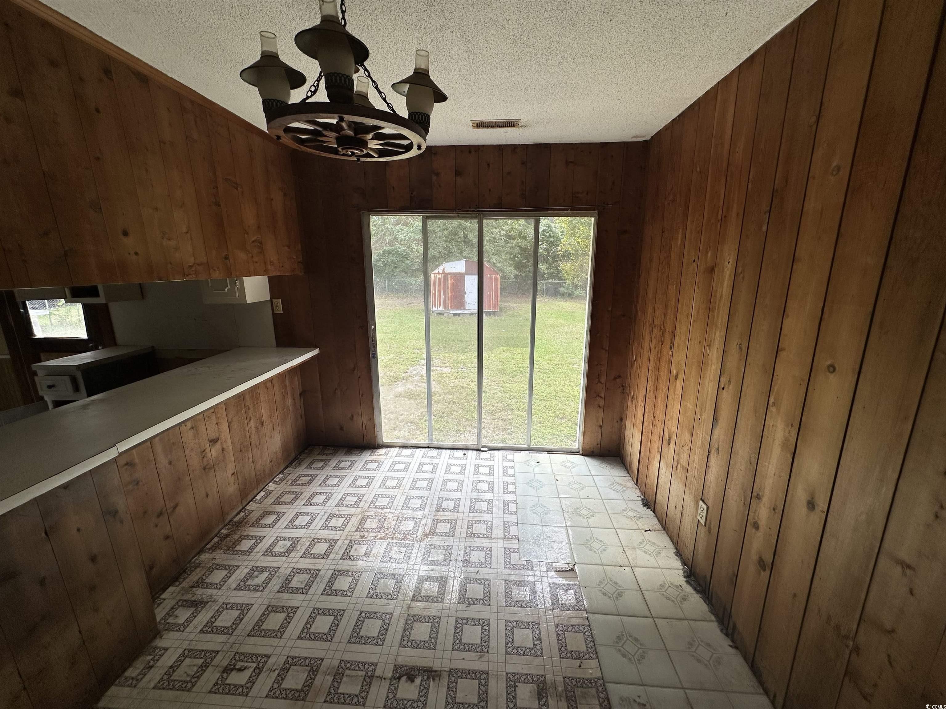 11185 Old Pee Dee Road Hemingway, SC 29554 - Photo 11 of 15 Kitchen with a chandelier, wood walls, a textured ceiling, hanging light fixtures, and light countertops