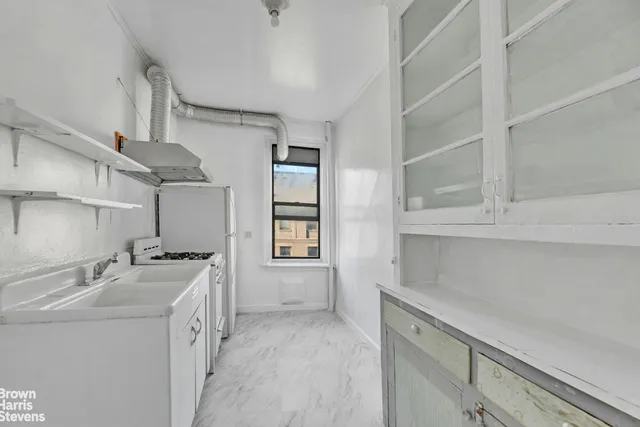 a kitchen with stainless steel appliances a sink a stove and white cabinets