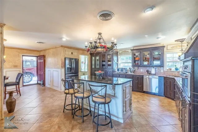 a kitchen with stainless steel appliances kitchen island granite countertop a refrigerator and cabinets