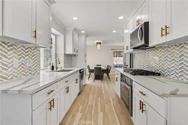 a kitchen with stainless steel appliances granite countertop a sink a stove and white cabinets