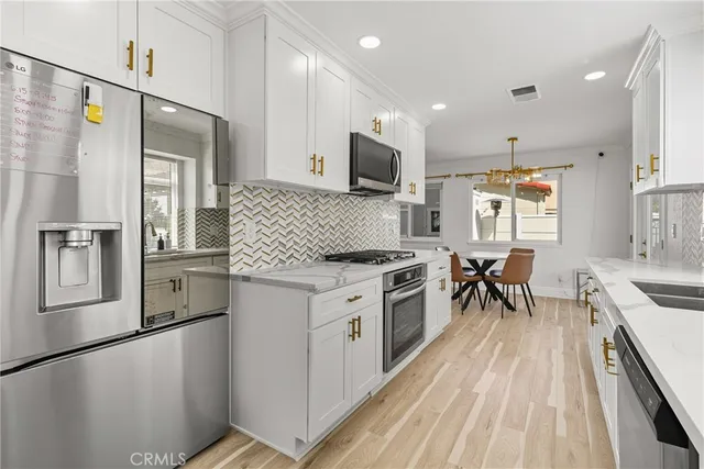 a living room with stainless steel appliances furniture a rug and kitchen view