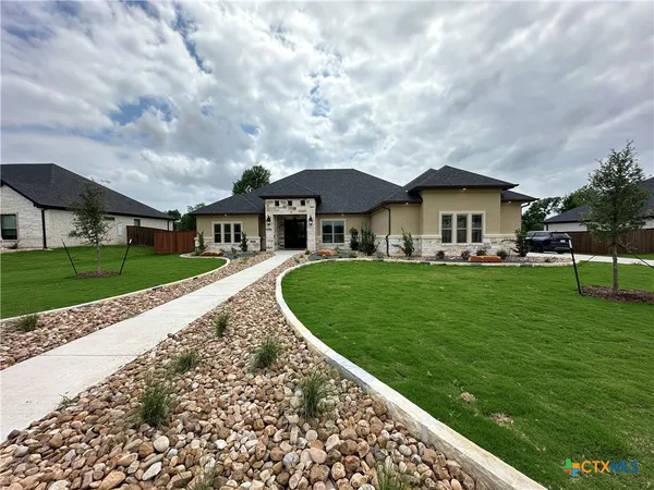 a front view of a house with a garden and trees