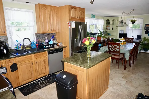 a kitchen with stainless steel appliances granite countertop a refrigerator a stove a sink dishwasher and white cabinets with wooden floor