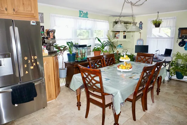 a view of a dining room with furniture a fireplace open kitchen view and a window