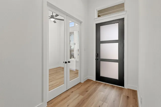 a view of an empty room with wooden floor and a window