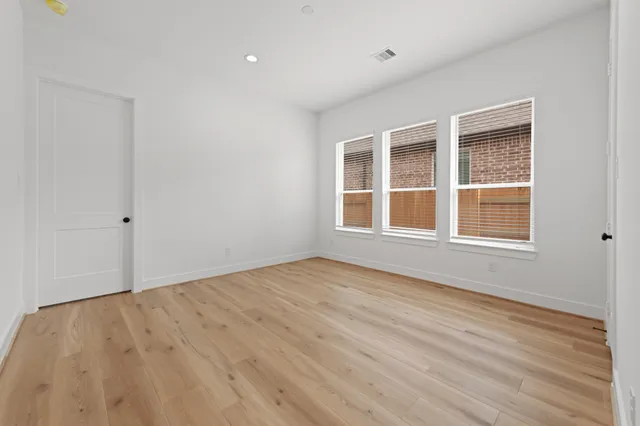 a view of an empty room with wooden floor and windows