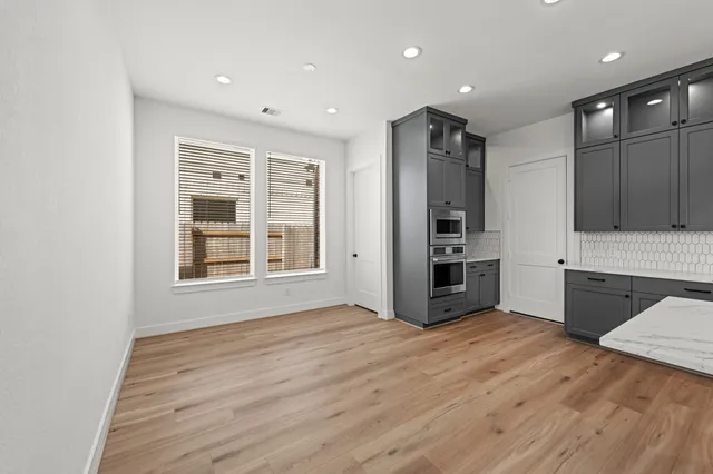 a view of an empty room with a kitchen and a window