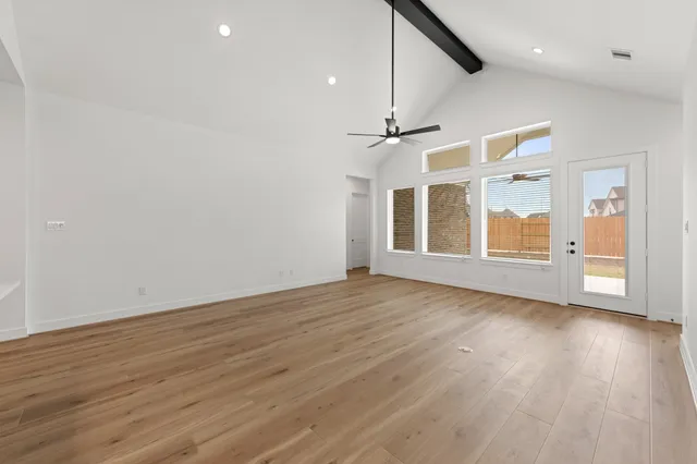 an empty room with wooden floor chandelier and windows
