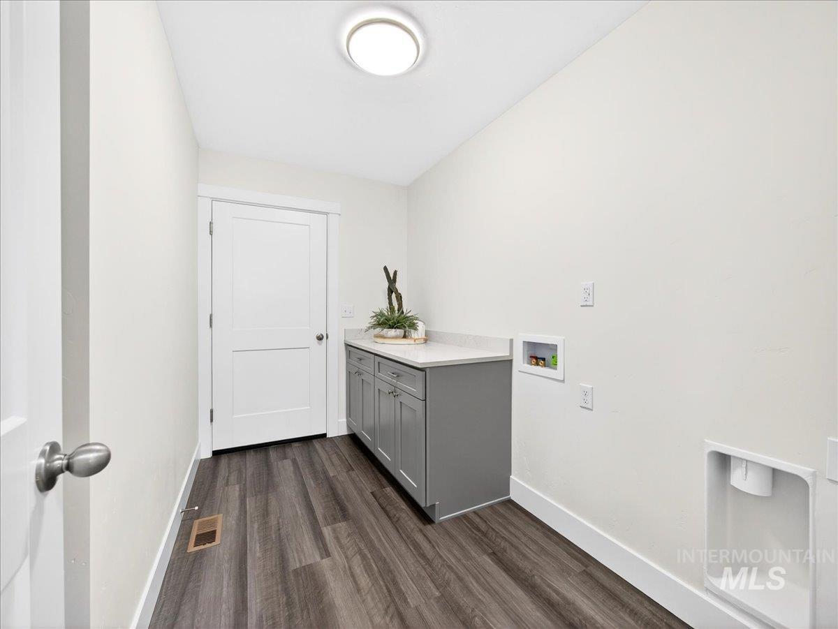 1410 Regency Way Emmett, ID 83617 - Photo 27 of 46 Laundry area featuring dark wood-style floors, washer hookup, and cabinet space