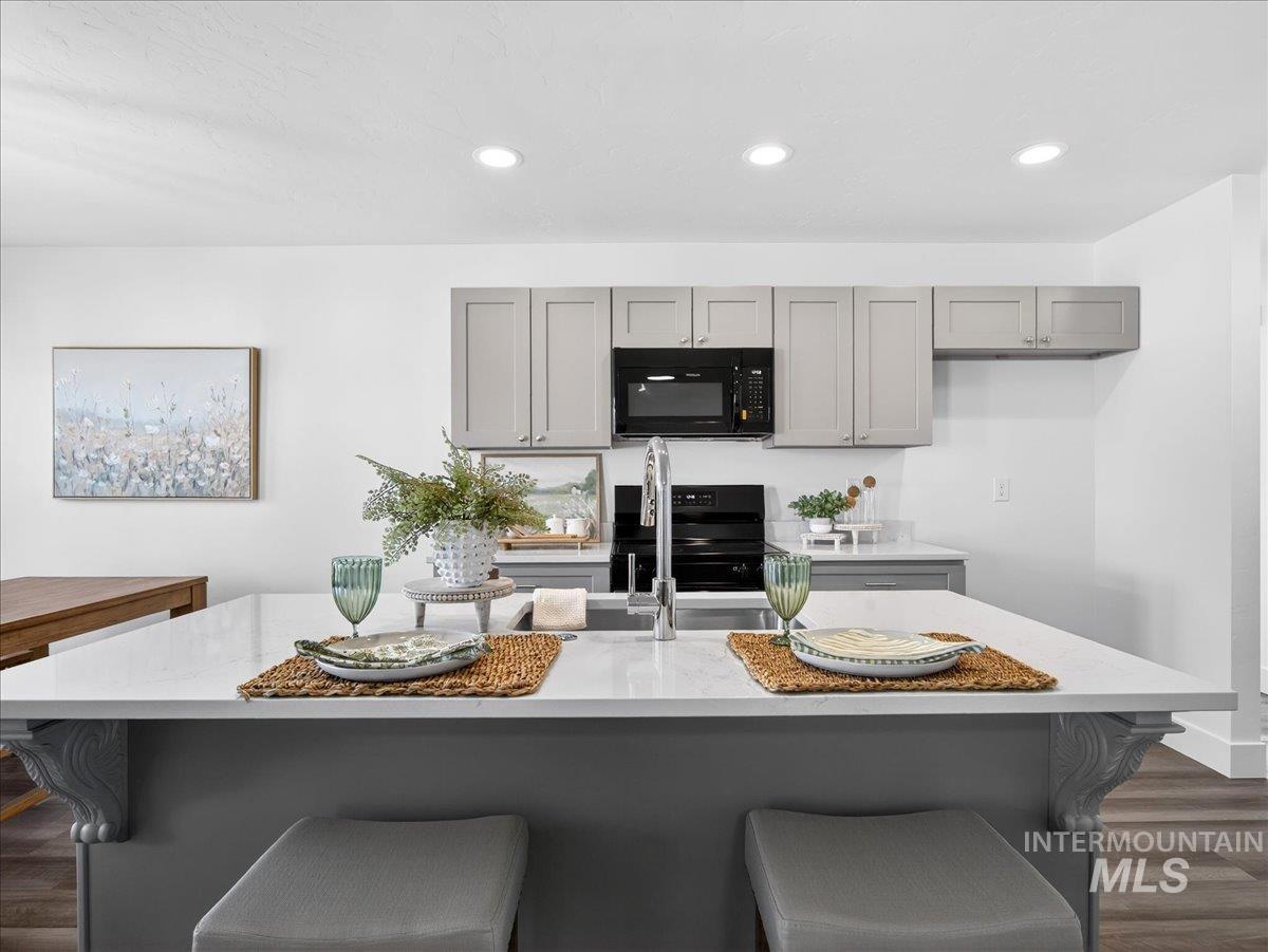 1410 Regency Way Emmett, ID 83617 - Photo 10 of 46 Kitchen featuring dark wood-style floors, gray cabinets, a breakfast bar area, black appliances, and recessed lighting